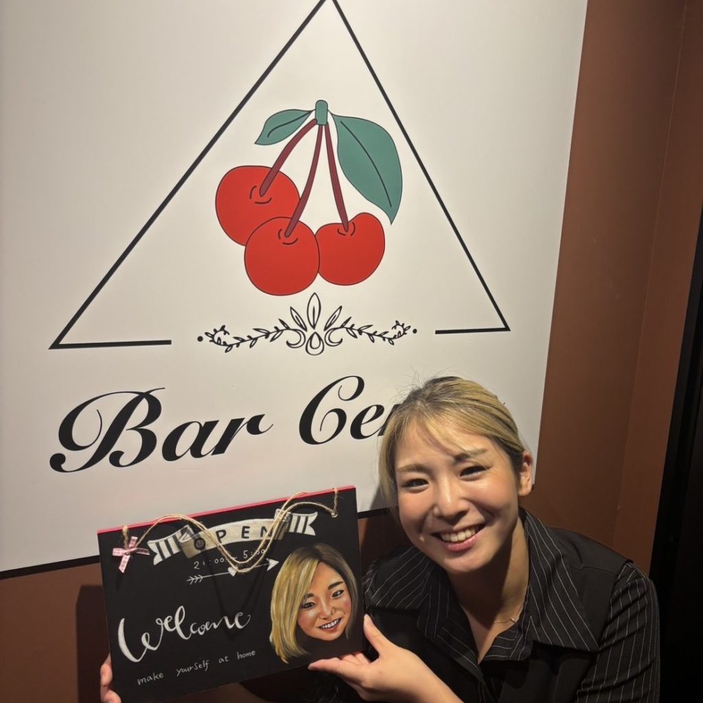 看板前でほほ笑む女性